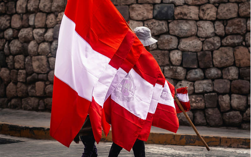 Children holding Peruvian flags infront of the brick wall