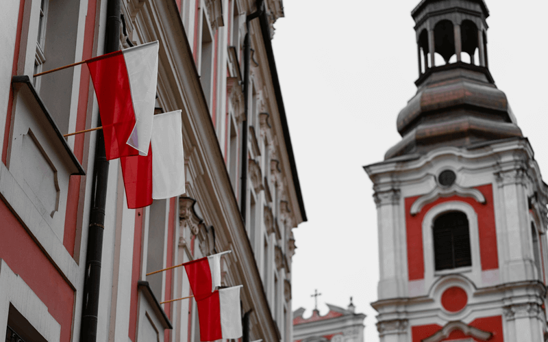 Flags of Poland outside the white and red Polish flag colored building