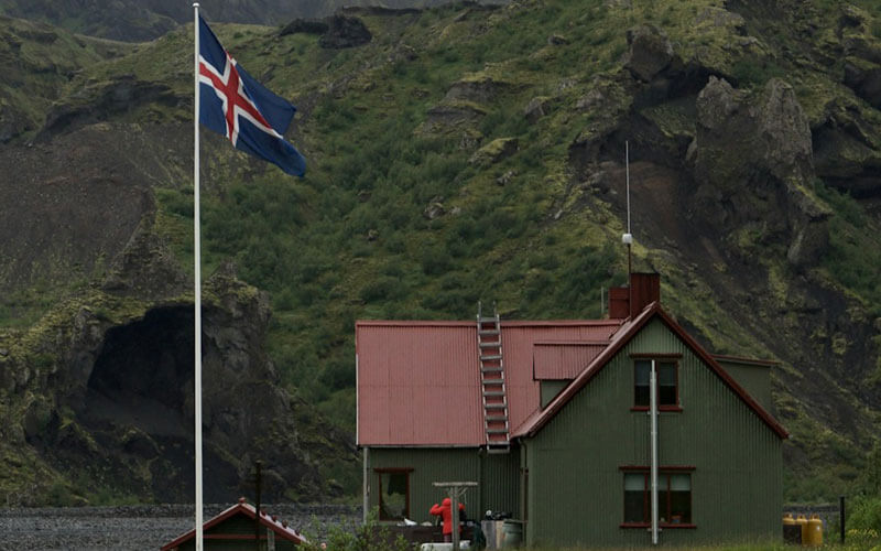 Iceland flag near the house at the mountains