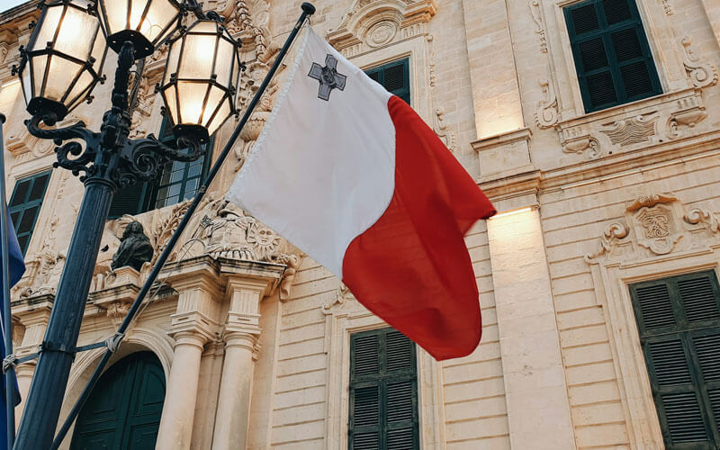 White and red flag of Malta at the lamp post infront of the building
