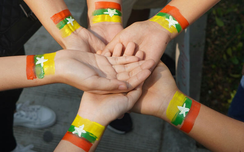 Yellow, green and red Myanmar flag painted on the hands