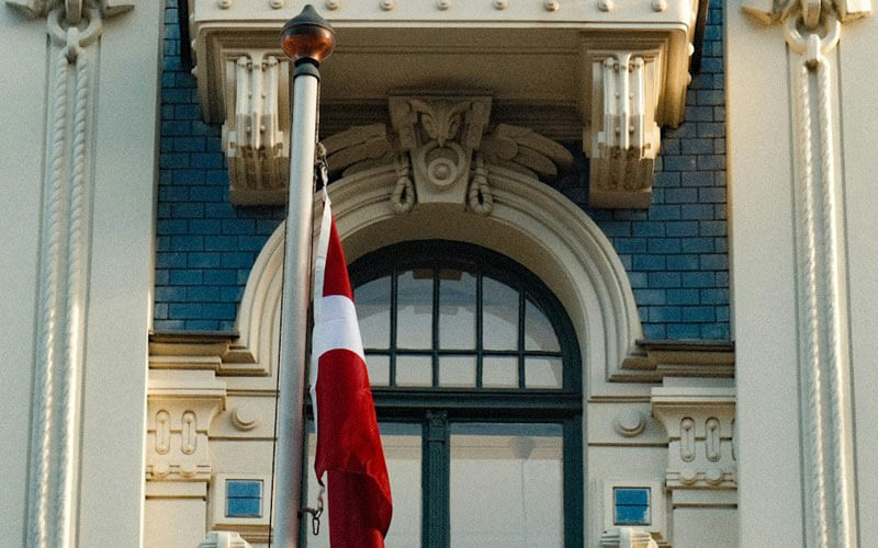 Red and white flag of Latvia infront of the historical building
