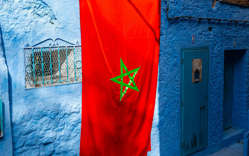 Red flag of Morocco hanging on the blue wall