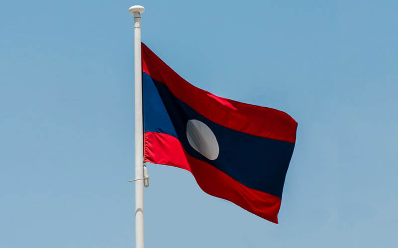 Red, white and blue flag of Laos flying in the wing