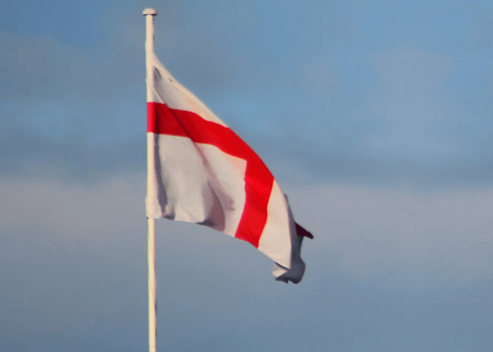 White and red flag of England flying high on the mast